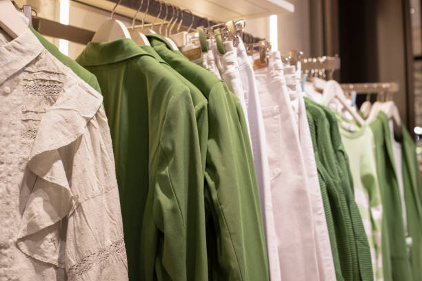 Green and white sustainable clothing items hanging on a rack in a boutique.